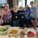 Five women smiling in a kitchen in front of a taco bar meal (photo credit Junior League of Boise)